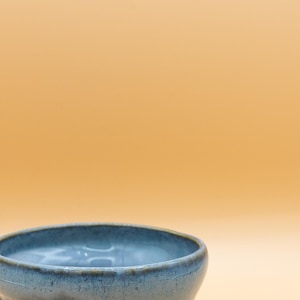 Könnte beinhalten: Ein blauer Keramik-Pflanztopf mit einem welligen, strukturierten Design. Der Topf ist aus Steinzeug und hat eine glasierte Oberfläche.