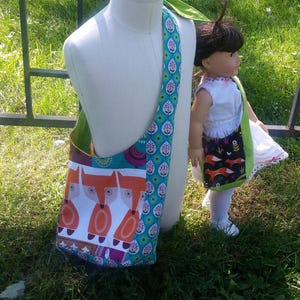 Può includere: Una borsa di tela colorata con una stampa di volpe. La borsa ha una tracolla lunga e si porta sulla spalla. La borsa è realizzata in tessuto patchwork con diversi motivi e colori.