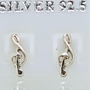 May include: Silver 92.5 earrings in the shape of a treble clef. The earrings are small and shiny, with a detailed design. The text "SILVER 92.5" is visible above the earrings.