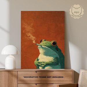 Op de afbeelding: Een rechthoekige wandkunstprint met een groene kikker met grote ogen, die een brandende sigaret vasthoudt met zichtbare rook tegen een effen, gebrand oranje achtergrond. Rechtsboven staat een logo met de tekst PiMi Art Studio.