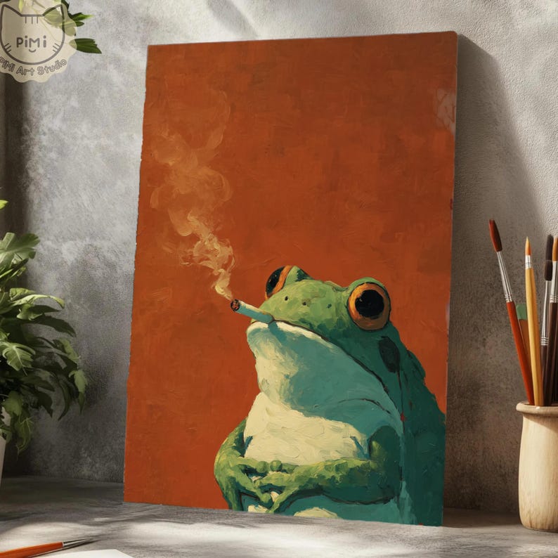 Op de afbeelding: Een rechthoekige canvasprint met een olieverfschilderij van een groene kikker met grote oranje ogen, die een brandende sigaret in de mond houdt met een sliert witte rook tegen een effen, getextureerde roestoranje achtergrond.