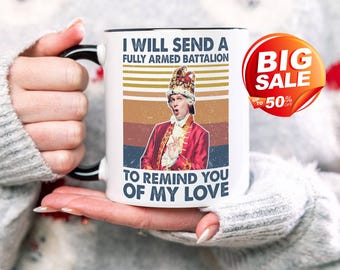 May include: White ceramic mug with a black handle and rim. The mug features a vintage-style image of a person in a red coat and crown, with text that reads "I WILL SEND A FULLY ARMED BATTALION TO REMIND YOU OF MY LOVE."