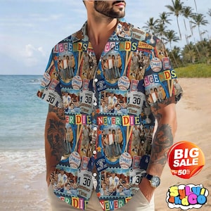 May include: A short-sleeved button-down shirt with a colorful collage design. The shirt features images of baseball players, baseballs, and the text "Legends Never Die" and "Summer Time". The shirt is worn on a beach.