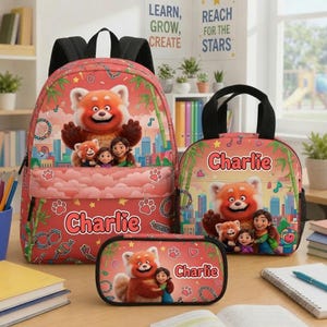 May include: A red backpack, lunch bag, and pencil case set featuring a cartoon red panda and a girl character with the name Charlie printed on each item. The design includes bamboo stalks, city buildings, and paw prints on a coral background.