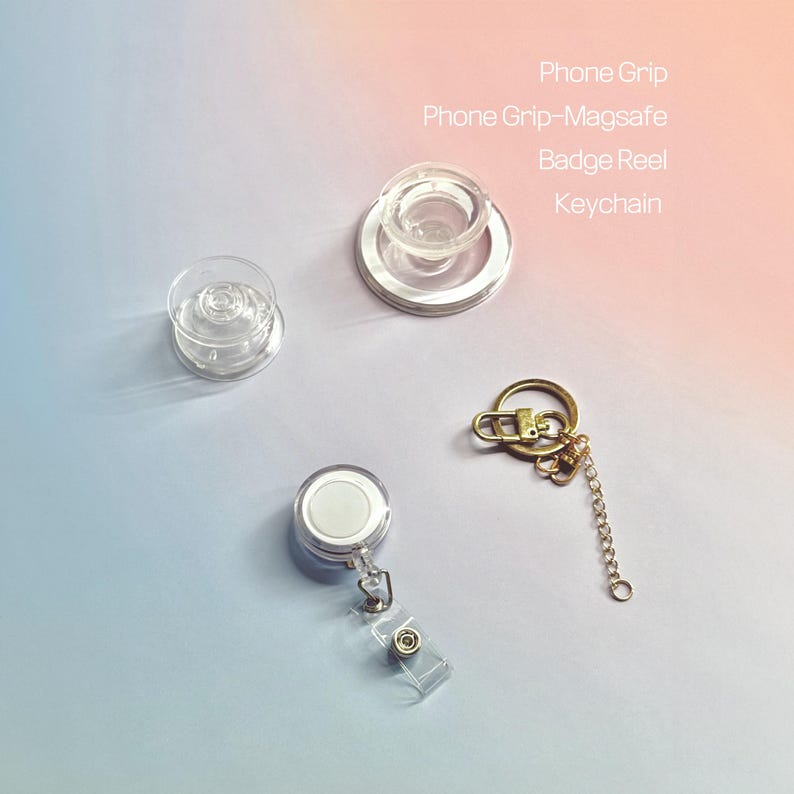 Puede incluir: Una variedad de accesorios, incluyendo un soporte para tel&eacute;fono transparente, un soporte para tel&eacute;fono-magsafe, un carrete para insignia y un llavero. El texto en la imagen dice: Phone Grip, Phone Grip-Magsafe, Badge Reel, Keychain. Fondo degradado.