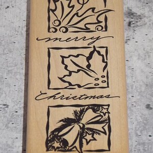 May include: A rectangular wooden stamp with three square designs and the words "merry Christmas" in cursive. The designs include holly leaves and a bow. The stamp is light brown with black ink.