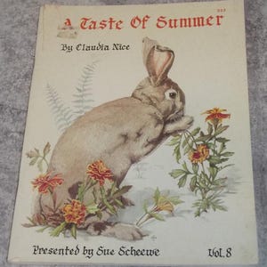 May include: Vintage book cover titled "A Taste of Summer" featuring a brown rabbit surrounded by orange and yellow flowers. The cover art is an illustration with text that reads "By Claudia Nice" and "Presented by Sue Scheewe".