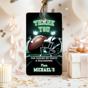 May include: A black tag with a football and helmet design. The tag reads "THANK YOU" and "FOR COMING MY PARTY! A TOUCHDOWN! From MICHAEL'S" in green text. A brown string is attached to the top of the tag.