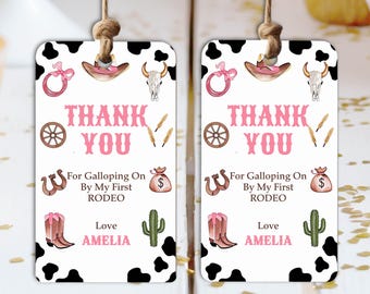 May include: Two cow-print gift tags with a rodeo theme. Each tag features a pink "Thank You" message, cowboy hat, horseshoe, cactus, and the name "AMELIA". The tags are connected by a natural twine.
