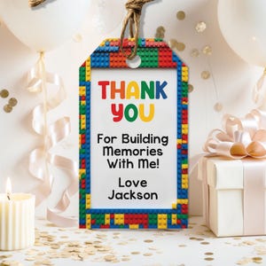 May include: A colorful gift tag with a Lego-themed border. The tag reads "THANK YOU" in red, yellow, and green, followed by "For Building Memories With Me! Love Jackson."