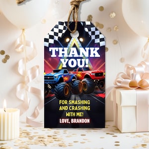 May include: A gift tag with a monster truck theme. The tag features a blue and red monster truck design with the words "THANK YOU!" and "FOR SMASHING AND CRASHING WITH ME! LOVE, BRANDON" printed on it. A checkered flag is at the top.