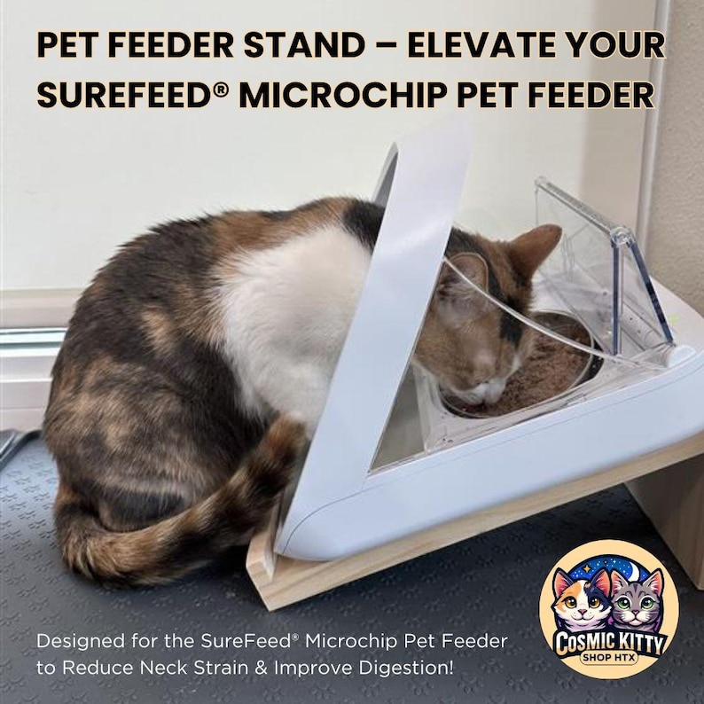 May include: A white elevated pet feeder stand designed for the SureFeed Microchip Pet Feeder. A calico cat is eating from the feeder. The stand is made of wood and has a white plastic top. The text "COSMIC KITTY SHOP HTX" is on a sticker on the stand. The text "Designed for the SureFeed Microchip Pet Feeder to Reduce Neck Strain & Improve Digestion!" is below the stand.