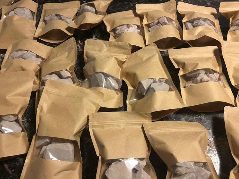 May include: Multiple brown paper bags with clear plastic windows, each containing a variety of small, irregularly shaped, light gray rocks.