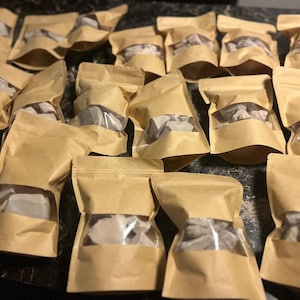May include: Multiple brown paper bags with clear plastic windows, each containing small, irregular pieces of light brown clay.