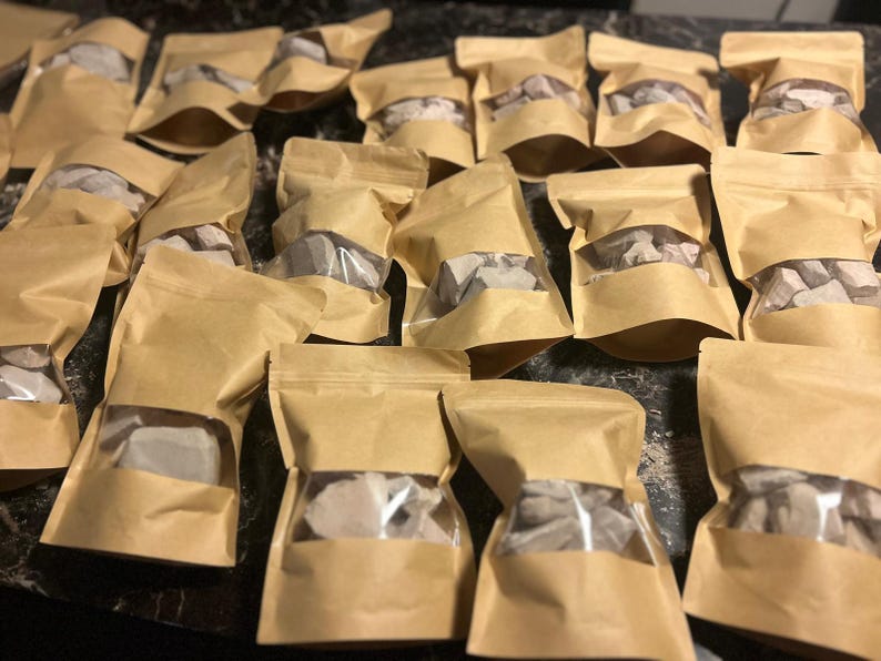 May include: Multiple brown paper bags with clear plastic windows, each containing small, irregular pieces of light brown clay.