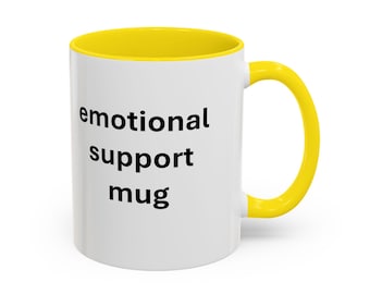 May include: White ceramic mug with a yellow interior and handle. The mug features the text "emotional support mug" in black, centered on the front. The mug is designed for hot or cold beverages.