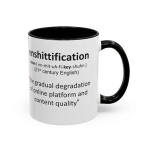 Könnte beinhalten: Weißer Keramikbecher mit schwarzem Innenraum und Griff. Der Becher zeigt das Wort "enshittification" in schwarzem Text, zusammen mit einer Definition und dem Satz "die allmähliche Verschlechterung der Online-Plattform und der Inhaltsqualität."
