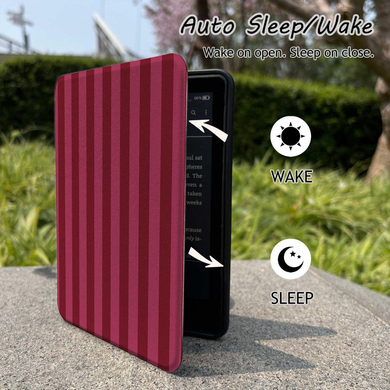 May include: A burgundy and dark red striped e-reader cover with the text "Auto Sleep/Wake" and "Wake on open. Sleep on close." The cover is open, revealing the e-reader screen. The image also shows a sun icon labeled "WAKE" and a moon icon labeled "SLEEP".
