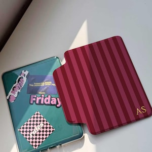 May include: Two phone cases. One is teal with stickers that say "Friday", "Thinking Night The Moments With You", and "Be You". The other is burgundy with vertical stripes and gold initials "AS".