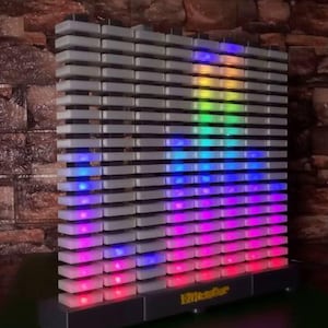May include: A rectangular, gray LED light display with horizontal bars. The display shows a spectrum of colors, including red, blue, green, and yellow. The base of the display has the word "Rittender" printed on it.
