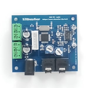 Può includere: Una scheda di circuito blu con vari componenti elettronici, tra cui morsettiere verdi, condensatori e un processore centrale. La scheda presenta il testo "Elmaster" e "LED Videin" stampati, insieme ad altri contrassegni tecnici.