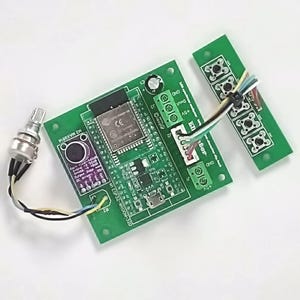 May include: A green circuit board featuring electronic components, including a microphone, a potentiometer, and a module with the text "CE". Wires connect the components. A separate green board with four circular components is also present.