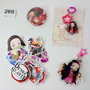 May include: A selection of anime-themed items, including stickers, a button badge, and keyrings. The stickers showcase characters and designs from the anime series. The keyrings feature pink star accents and anime character charms. The button badge is round with a character design.