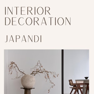 Puede incluir: Un concepto de diseño de interiores minimalista llamado "Japandi" con un jarrón de cerámica blanca con ramas secas sobre un pedestal de madera oscura y un pequeño taburete de madera. El fondo muestra un comedor con una mesa y sillas de madera.