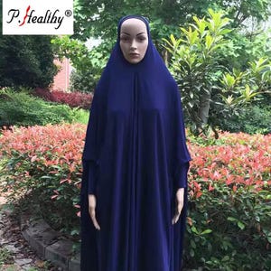 Può includere: Un'abaya blu scuro a figura intera con maniche lunghe e un cappuccio integrato che copre la testa e le spalle. L'indumento è esposto su un manichino, mostrando una consistenza del tessuto liscia e una silhouette ampia e fluida.