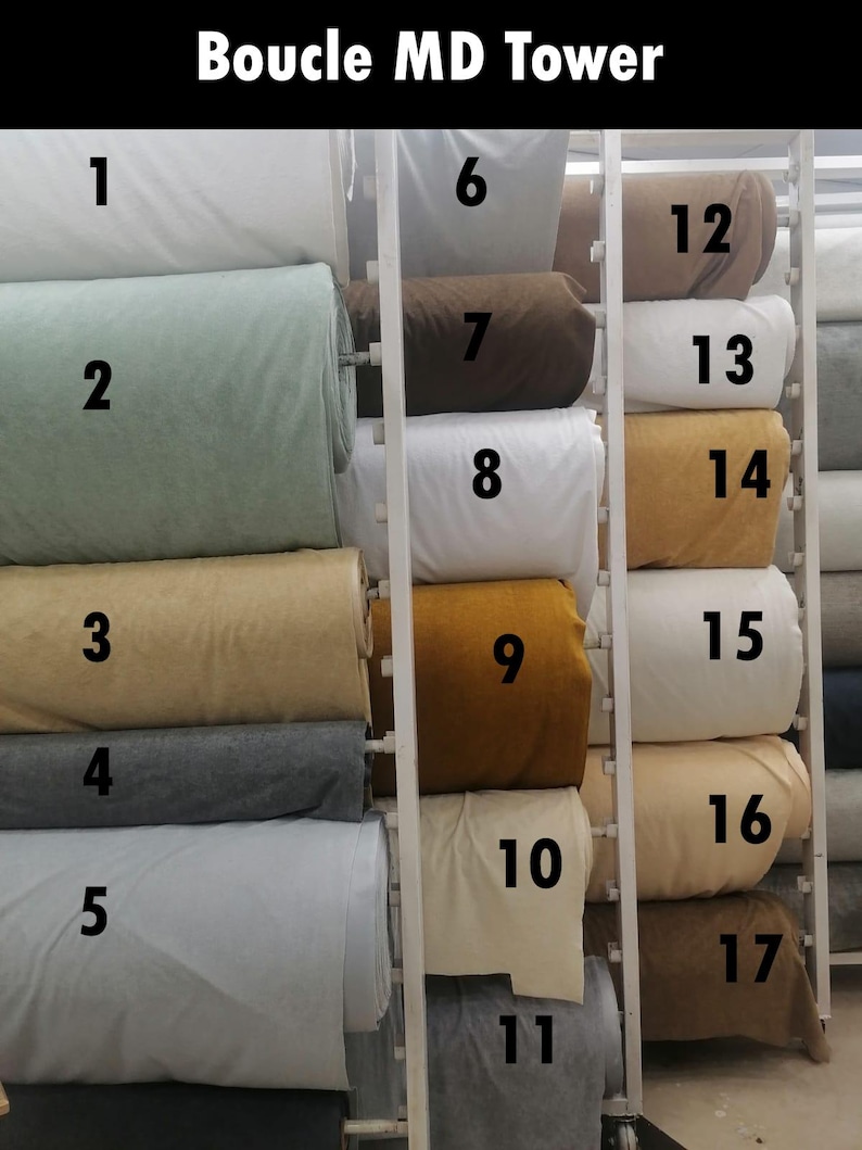 May include: A display of fabric rolls in various colors, including white, green, tan, gray, and gold. The text "Boucle MD Tower" is at the top. The rolls are numbered 1 through 17.