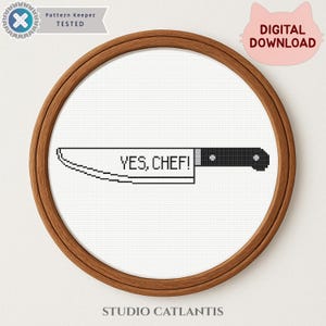 May include: Cross-stitch design of a chef's knife with the text "YES, CHEF!" in black and white. The design is set in a wooden embroidery hoop. A pink cat-shaped "DIGITAL DOWNLOAD" sticker is in the upper right corner.