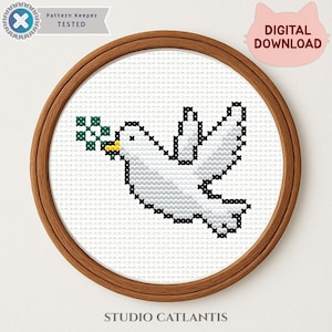May include: A cross-stitch pattern of a white dove carrying a green olive branch in its beak, set in a wooden embroidery hoop. The words "DIGITAL DOWNLOAD" are in a pink cat-shaped bubble. The text "Pattern Keeper TESTED" and "STUDIO CATLANTIS" are also visible.