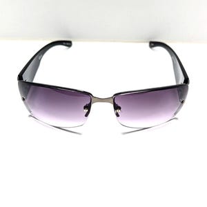 May include: Rimless sunglasses with a gradient purple tint. The frames are black with a silver bridge. The sunglasses have a sleek, modern design.