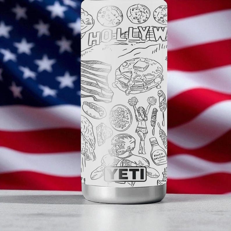 Puede incluir: Un vaso t&eacute;rmico blanco con base plateada, con ilustraciones en blanco y negro de iconos estadounidenses como panqueques y un jugador de f&uacute;tbol americano. Tambi&eacute;n es visible la palabra "HOLLYWOOD".