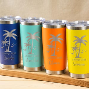 May include: Four stainless steel tumblers in blue, teal, orange, and yellow, each with a silver palm tree design and personalized text. The tumblers are on a wooden surface, ideal for personalized gifts.