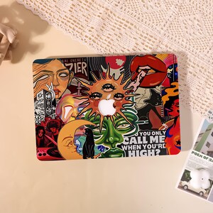 Può includere: Una skin per laptop con un vivace collage di illustrazioni surreali, tra cui un sole centrale con occhi, una luna crescente, un gatto nero, labbra rosse e un volto verde. Il testo recita "DO YOU ONLY CALL ME WHEN YOU'RE HIGH?" e "BEASTIE BOYS."