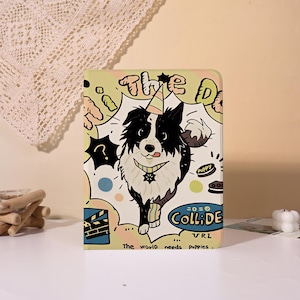 Può includere: Una custodia rettangolare per tablet con un'illustrazione a cartoni animati di un cane bianco e nero che indossa un cappellino da festa. Il design include il testo "THE DOG", "COLLIDE" e "The world needs puppies" in stile fumetto con grafiche.