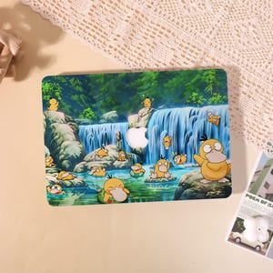 May include: A rectangular laptop skin featuring a vibrant illustration of multiple yellow Psyduck characters in a lush forest setting with a waterfall, rocks, and a stream. The design includes a central cutout for an Apple logo on the device.