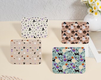 May include: Four Halloween-themed badge holders with rounded corners and a hole at the top. Each features a different pattern: ghosts, pumpkins, witch hats, and black cats. The backgrounds are beige, tan, and light blue.