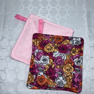 May include: Two quilted pot holders. One is pink and the other has a floral pattern with pink, orange, and white roses.