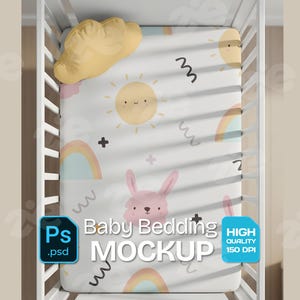May include: A baby bedding mockup featuring a white sheet with a whimsical design of smiling suns, rainbows, and a pink bunny. A yellow cloud-shaped pillow rests on the crib. The sheet has black squiggles and plus signs. The text "Baby Bedding MOCKUP" is visible.