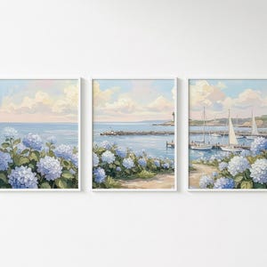 May include: Three framed art prints depicting coastal scenes. Each print features a serene seascape with blue hydrangeas in the foreground. One print shows a lighthouse, and another shows sailboats in the harbor.