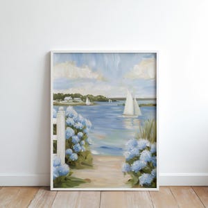 May include: Framed painting of a coastal scene with sailboats on the water. The artwork features a white picket fence, blue hydrangeas, and a sandy path leading to the water. The sky is a light blue with fluffy white clouds.