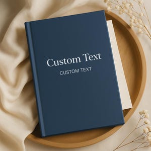 Puede incluir: Un cuaderno de tapa dura azul marino con el texto "Custom Text" y "CUSTOM TEXT" en letras blancas.