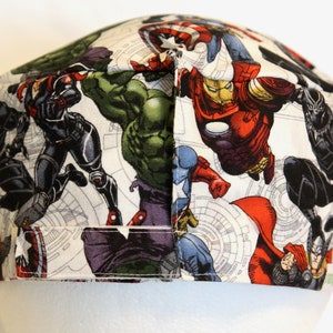 May include: A white fabric hat with a pattern of various Marvel superheroes, including Iron Man, Hulk, Captain America, Black Widow, and Black Panther.