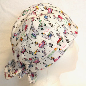 May include: White surgical scrub hat with a colorful llama print. The hat has a tie at the back and the text "mango moods" is visible on the side.