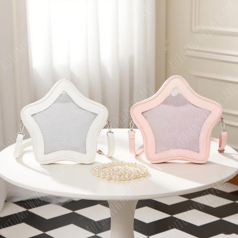 Puede incluir: Dos bolsos cruzados en forma de estrella, uno blanco y otro rosa, sobre una mesa blanca. Cada bolso tiene un centro de malla y una correa a juego. Un collar de perlas descansa entre ellos. Un accesorio &uacute;nico.