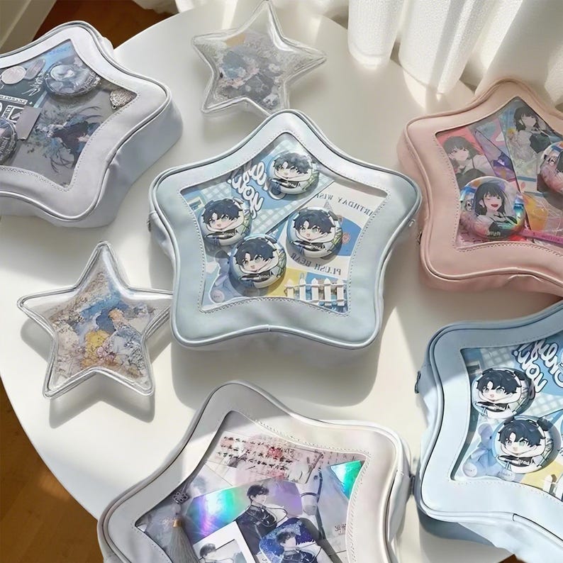 Puede incluir: Una colecci&oacute;n de bolsos y objetos decorativos en forma de estrella. Los bolsos son de varios colores pastel, incluyendo blanco, azul y rosa, con paneles transparentes que muestran pines y obras de arte. Algunos art&iacute;culos son contenedores transparentes en forma de estrella llenos de im&aacute;genes.