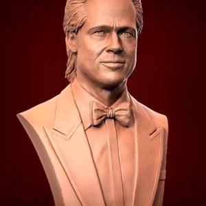 Puede incluir: Una escultura de busto de una persona con cabello castaño corto que lleva un traje y una corbata de lazo. La escultura está hecha de un material marrón claro.