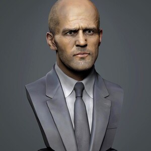 Könnte beinhalten: Eine Büste eines Mannes mit Glatze, der einen grauen Anzug, ein weißes Hemd und eine graue Krawatte trägt. Die Büste steht auf einem dunkelgrauen Sockel vor einem grauen Hintergrund. Der Mann hat einen ernsten Gesichtsausdruck.